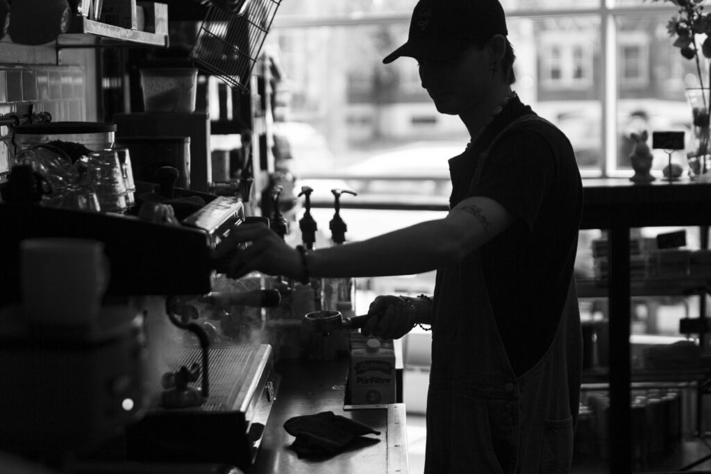 Un barista prépare un café à la machine espresso, photo en noir et blanc