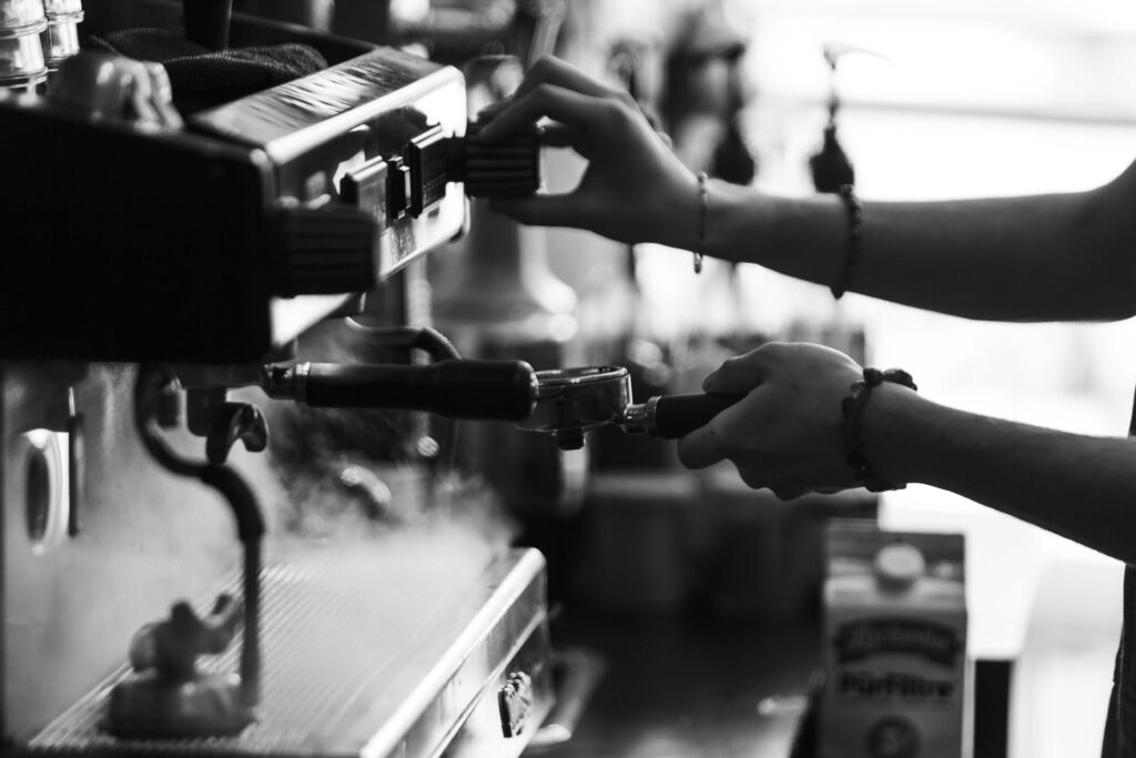 A barista’s hands locking the portafilter into the espresso machine, in black and white